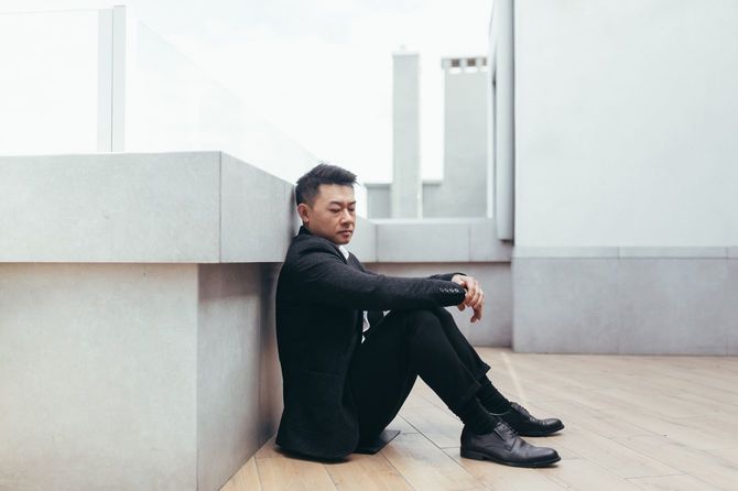 屋上に座っている疲れたビジネスパーソン