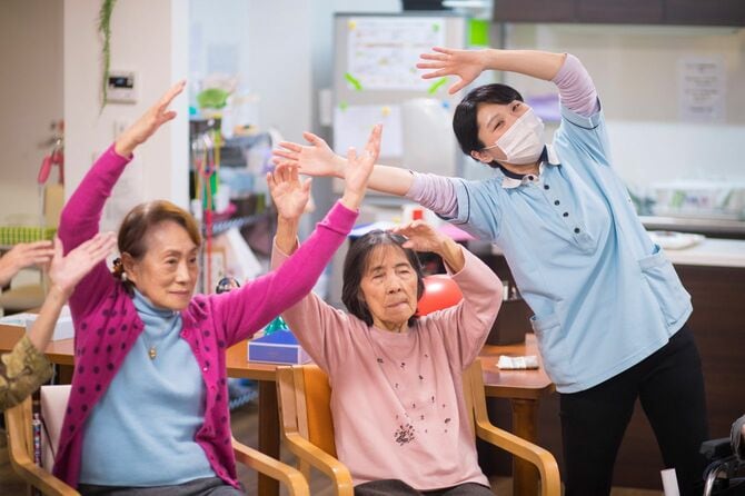 年配の女性と女性看護師のストレッチ