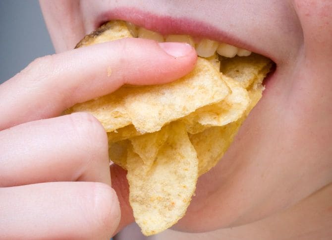ポテトチップスを頬張る女性の口元