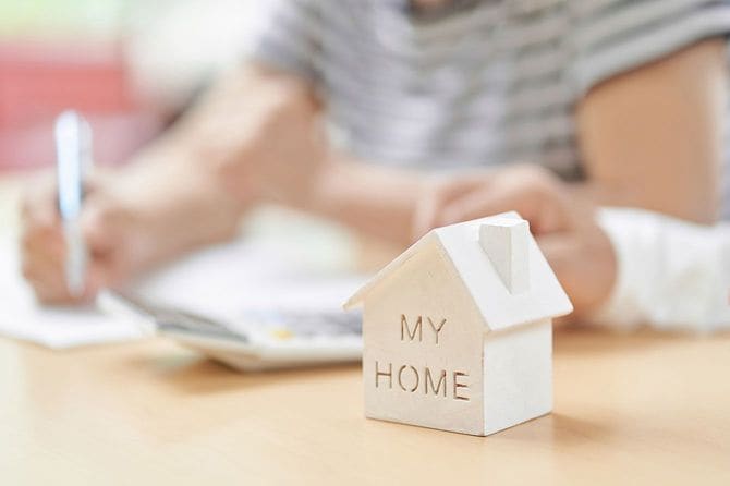 「MY HOME」と書かれた家の模型と、書類に記入する人