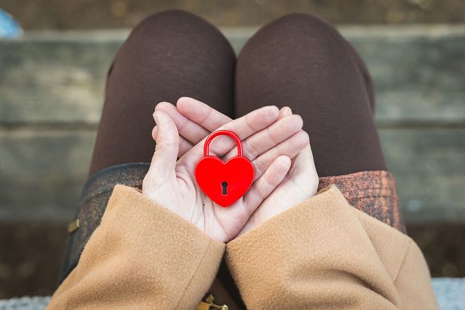 女性の手は心臓の形で閉じられた赤い南京錠を握る