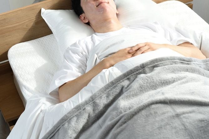 ベッドで仰向けに寝ている男性