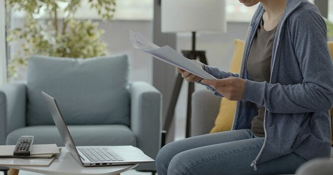 パソコンに向かいながら書類を見る人