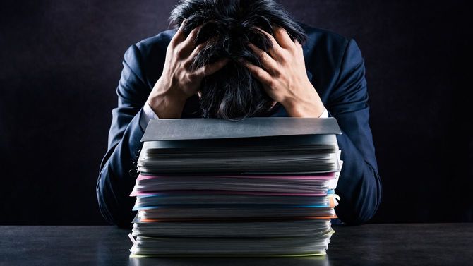 あまりの仕事量に頭を抱えるビジネスパーソン