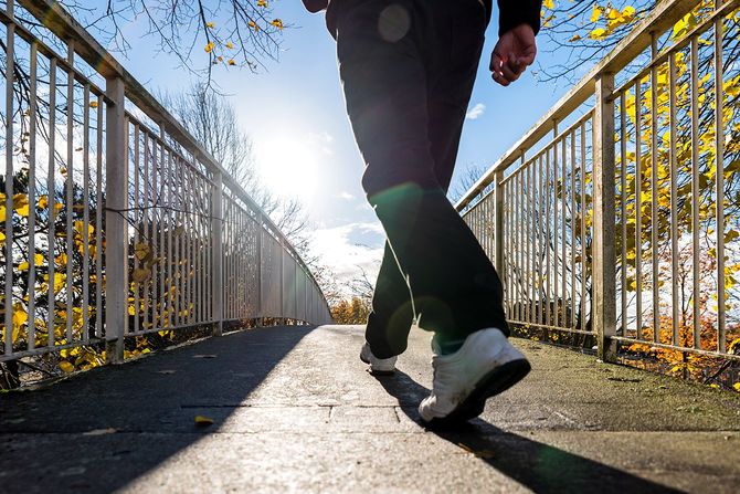 英国の秋に歩道橋の上を歩く男の明るい晴れた朝の景色。
