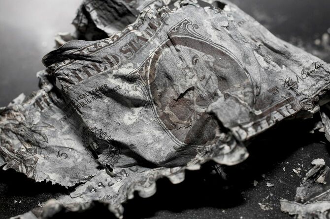 灰になって崩れる米ドル紙幣