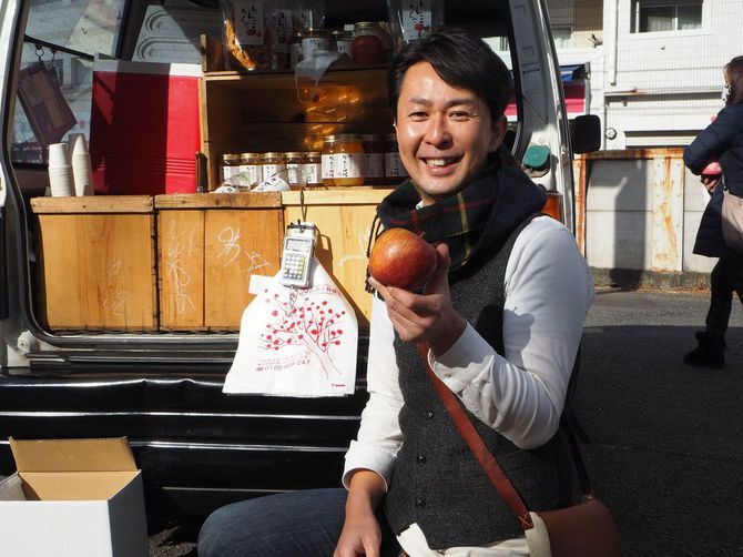 笑顔でリンゴを差し出す片山玲一郎さん