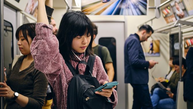 日本の地下鉄車内、スマホを見つめる人たち