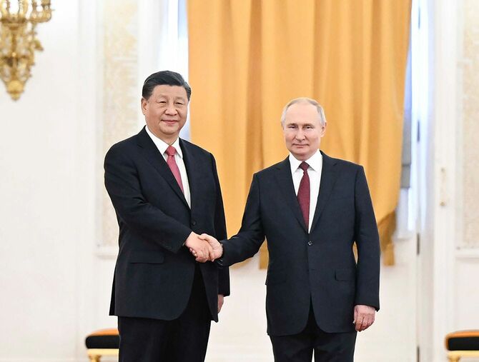2023年3月21日、プーチン氏（右）が行った習近平氏の歓迎式典で、握手しながら記念撮影に応じる両首脳。
