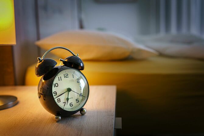 ベッドサイドのテーブルに置かれた目覚まし時計