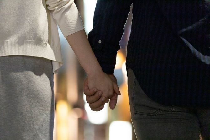 手をつないでいる男女のバックビュー