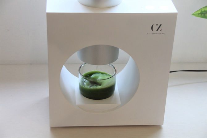 碾茶の粉が回転するコップの水に落ちて混ざり、抹茶ドリンクが完成