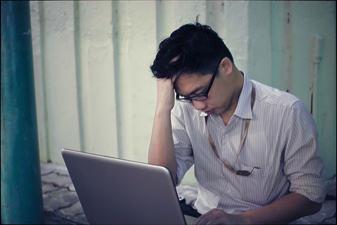 ラップトップを開いて頭を悩ませるサラリーマン