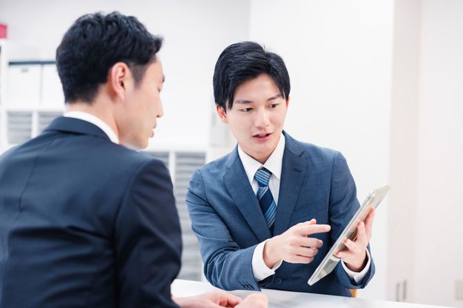 カウンターでタブレット端末を使って説明するビジネスマン
