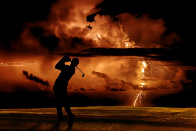 雷が鳴る中ゴルフする男性