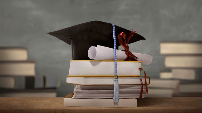 摘んだ書籍の上に学位帽
