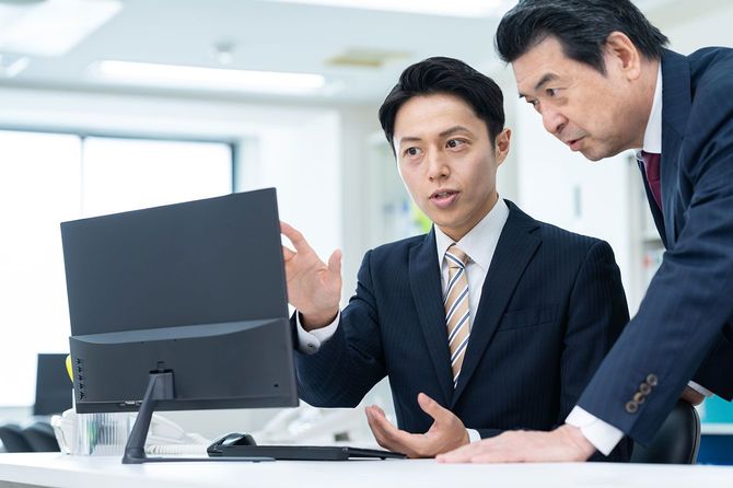 パソコン画面を見ながら話をする2人のビジネスマン