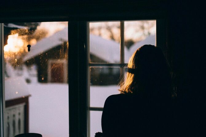  晴れた冬の日に窓の外を見ている女性