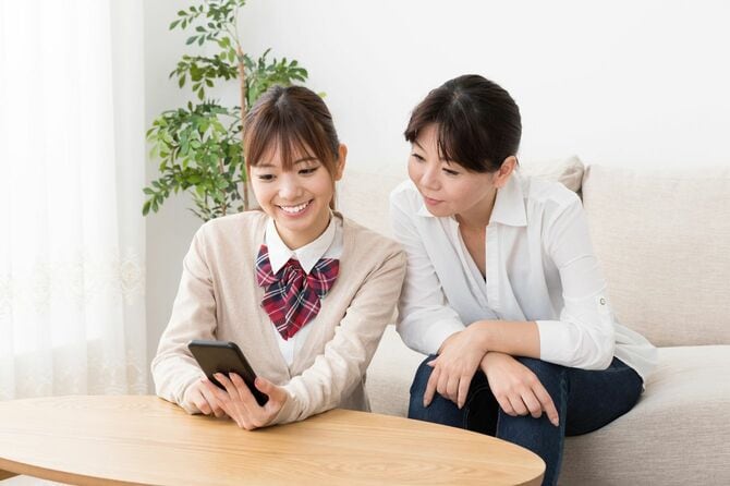 リビングで母親と一緒にスマホを見ている女子高生