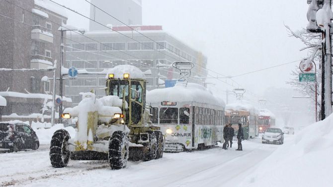 大雪に見舞われ運休となり、線路上の除雪作業を待つ路面電車の列＝2021年1月8日午後、JR富山駅前