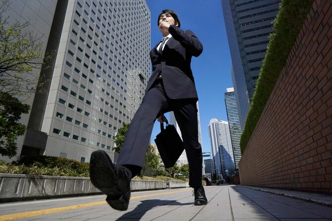 日本人男性ビジネスマンがオフィス街をきびきびと歩く