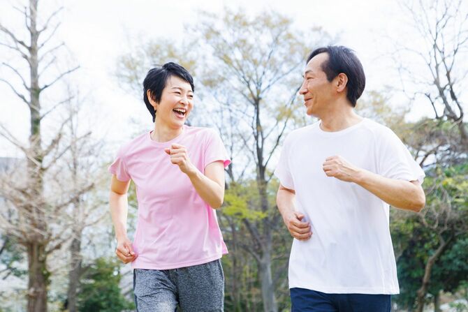 公園でジョギングするスポーツウェアを着たシニアの日本人夫婦