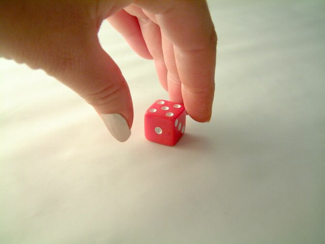 赤いサイコロを掴もうとする指