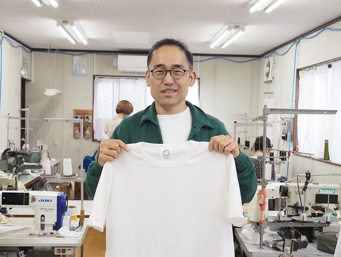 三恵メリヤスの三木健社長。手に持つのは「EIJI」のTシャツだ