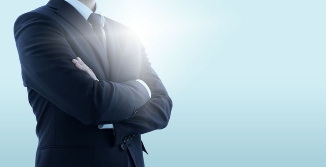 日の当たる場所で自信ありげに腕を組む男性