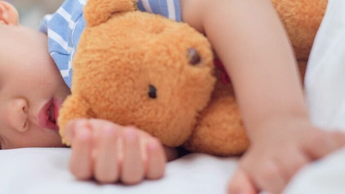ぬいぐるみを抱いて眠る赤ちゃん