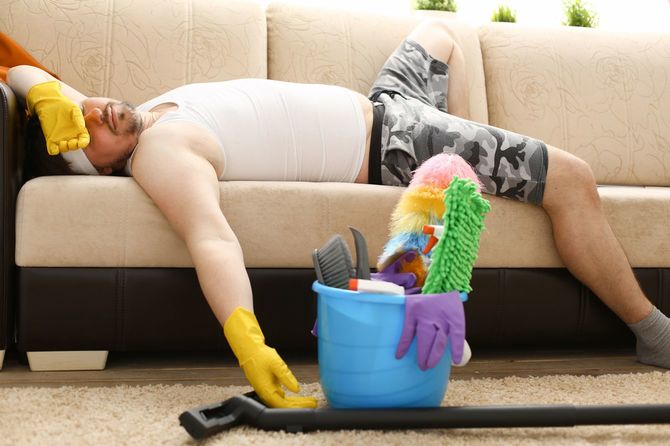 カラフルな掃除道具と、ソファにぐったりと横たわる男性