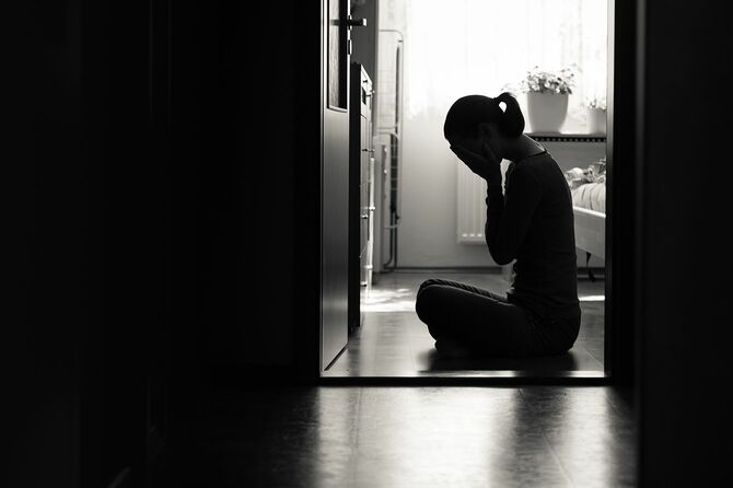 悲しい感情や感情を表現する床に座っている若い女性
