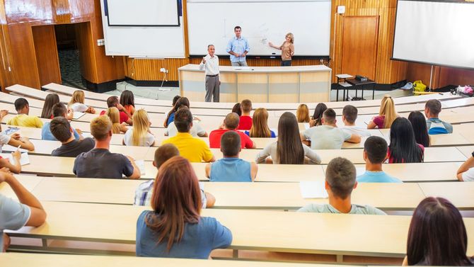 大学の大教室で講義をする教授やアシスタントたち