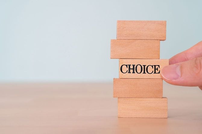 「CHOICE」と書かれたブロックを持つ人の手