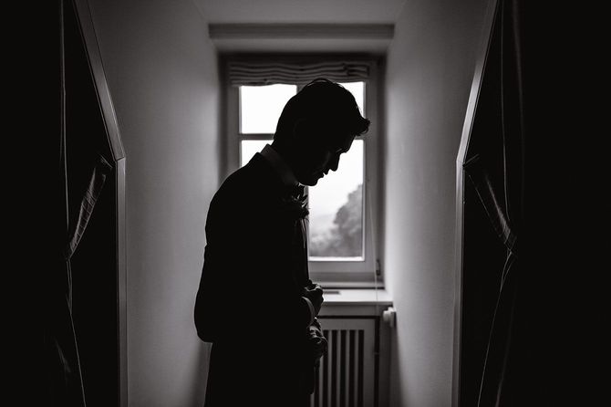 暗い部屋の窓際に立つ男性