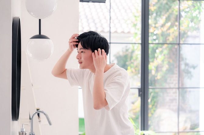 鏡の前で身だしなみを整えている若い男性