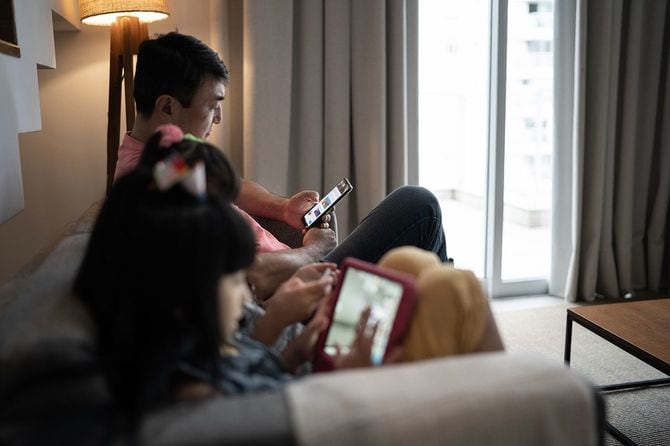 自宅で電子機器を使用する父と娘