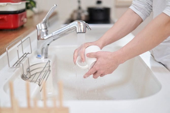 台所でカップを洗う男性の手元