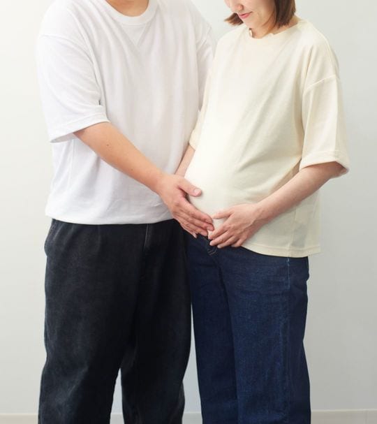 妊娠中の妻のおなかに手を添える男性