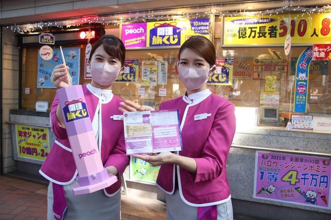 ピーチの新しい商品「開運旅くじ」を紹介する客室乗務員