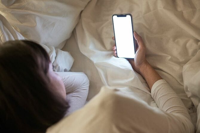 ベッドでスマホを見る女性