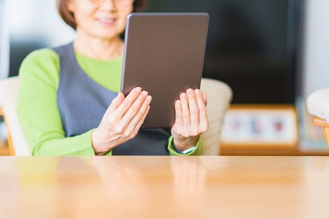 タブレット端末を見て笑顔を浮かべるシニア女性