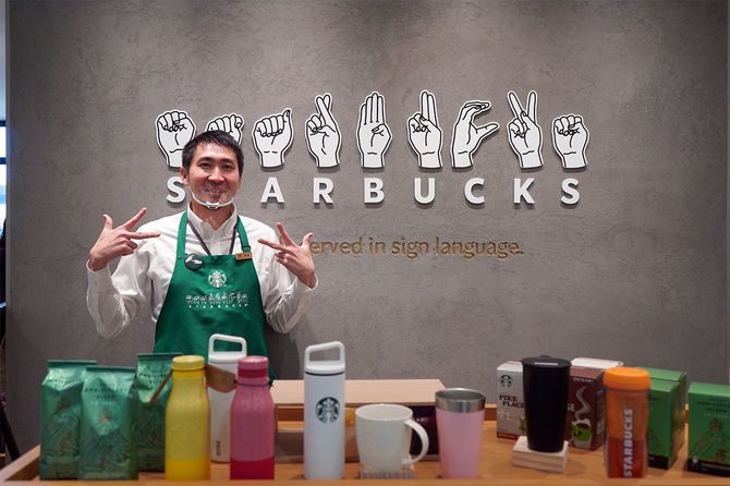 nonowa国立店の店頭。ストアマネージャーの伊藤真也さんに手話で“スターバックス”を表してもらった