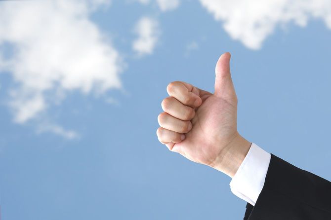 ビジネスマンの親指は、青空の背景に