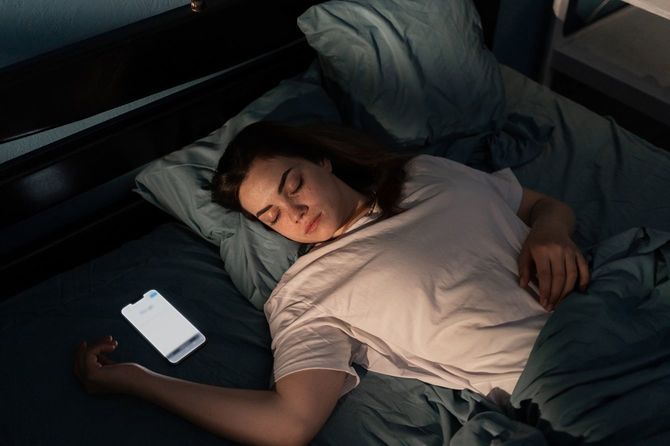 枕のそばに画面が明るいままのスマホ