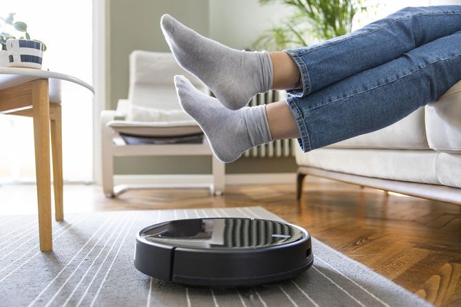 ロボット掃除機を通すために床から足を持ち上げている人