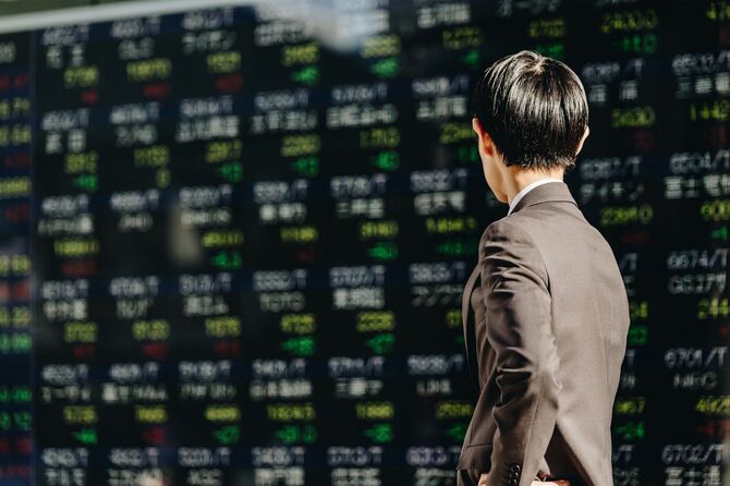 株価ボードを眺める男性の背中