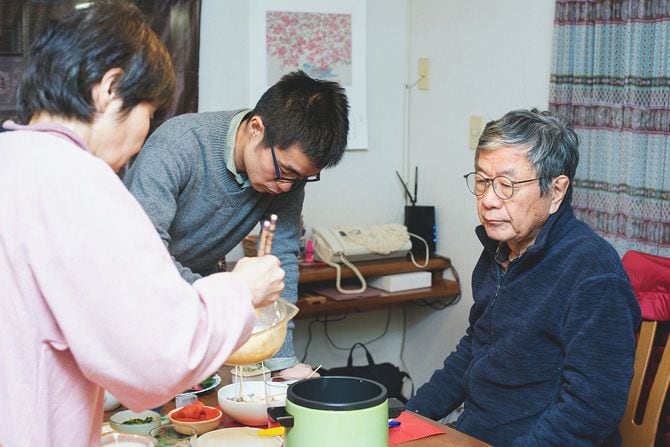 一緒に夕食を準備している先輩夫婦とその成人の息子。