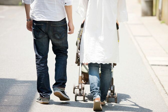 ベビーカーを押しながら散歩をする夫婦