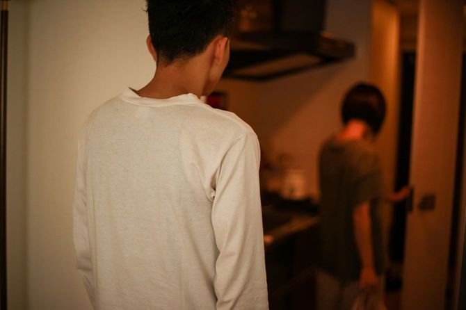 家を出ていく女性を見つめる男性の後ろ姿